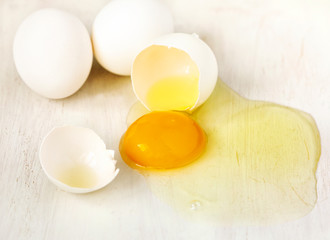 Cracked egg with egg shell, egg yolk and egg white on white background