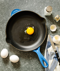 Raw chicken egg in a frying pan.