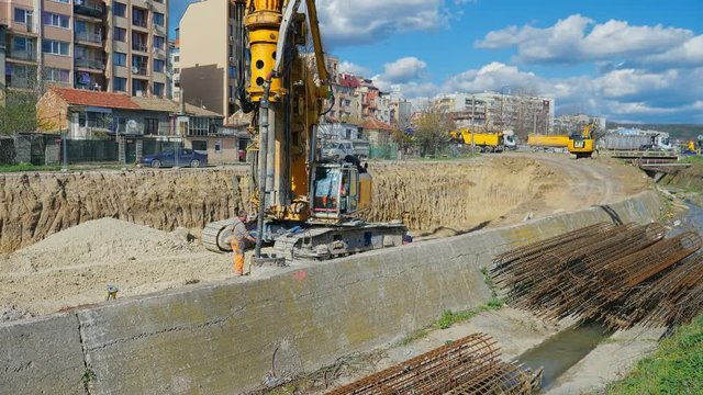 Heavy big excavator break trough holes for concrete colones for new road in construction site. Building a new streets in urban area, city town