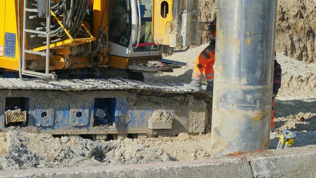 Heavy big excavator break trough holes for concrete colones for new road in construction site. Building a new streets in urban area, city town