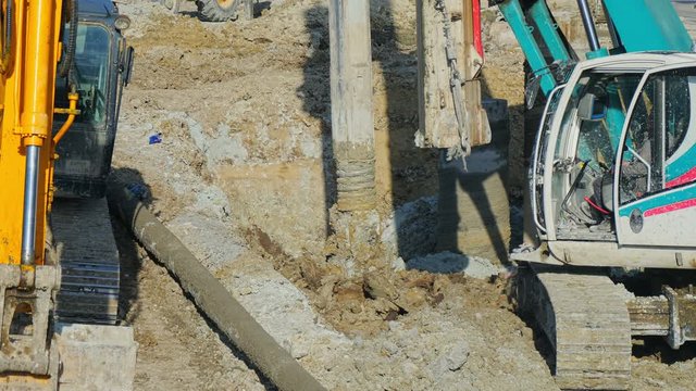 Heavy big excavator break trough holes for concrete colones for new road in construction site. Building a new streets in urban area, city town