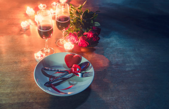 Valentines dinner romantic love concept Romantic table setting decorated with Red heart fork spoon on plate and couple champagne glass roses