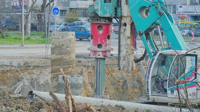 Heavy big excavator break trough holes for concrete colones for new road in construction site. Building a new streets in urban area, city town