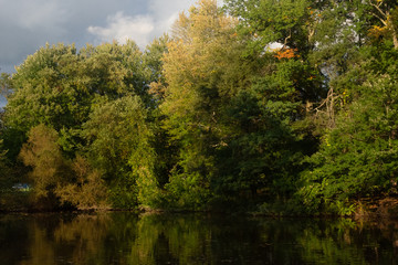 wide angle view of lake lined with forest trees on an autumn afternoon