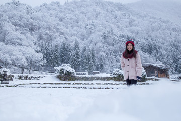 Happy Girl in Shirakawa-go village area on winter during snowing, with traditional House Gassho style and one of UNESCO world heritage sites, Gifu, Japan
