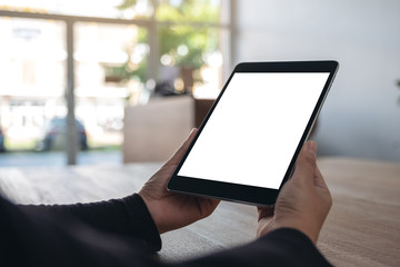 Mockup image of hands holding black tablet pc with blank white screen while sitting in office