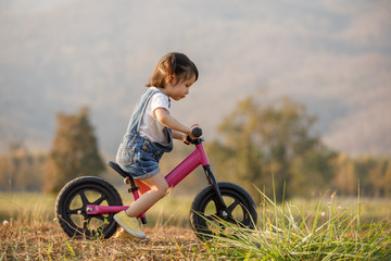 Happy child riding a bike. Little girl on a pink bicycle. Healthy preschool children summer activity. Kids playing outside. Little girl learns