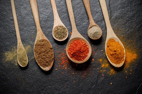 Herbs and spices and the spoon over black stone background. Top view