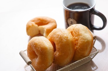Sugar donut and cup of black coffee