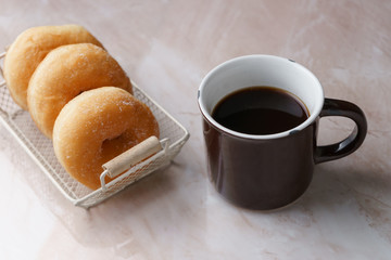 Sugar donut and cup of black coffee