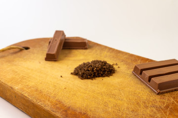 Chocolate bars and coffee on a rustic wooden board.