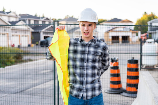 Young Construction Worker Putting On His Safety Gear At A Job Site.