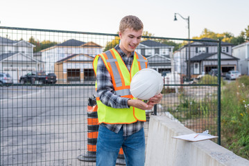 Young construction worker putting on his safety gear at a job site.