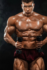 Fototapeta na wymiar Brutal strong muscular bodybuilder athletic man pumping up muscles with dumbbell on black background. Workout bodybuilding concept. Copy space for sport nutrition ads.