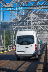 Compact cargo mini van for small business and delivery running on silver truss bridge