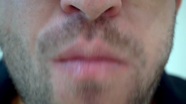 A man in glasses with stubble eats a slice of pizza in a cafe. Extrime close-up