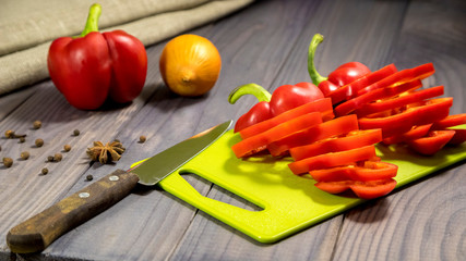 Three sweet red peppers with onion on the table. Process of cooking.
