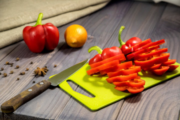 Three sweet red peppers with onion on the table. Process of cooking.