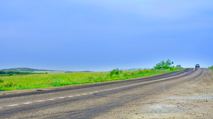 Rear View of a Car Speeding On Asphalt Road in Countryside to Escape Summer Thunderstorm.  Stormy Sky. Road Signs along the Route.