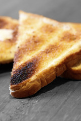 Pieces of white bread toast with butter on a wood surface with selective colour