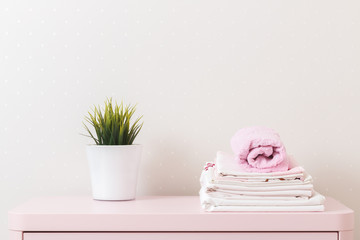 A pile of clean ironed bedding and a towel lies on the dresser.