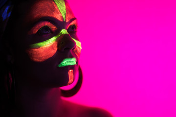 Fashion sexy dancer in neon light. Fluorescent makeup glowing under ultraviolet light. Night club,...