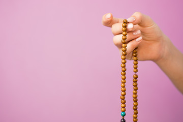 Woman, lit hand close up, counts Malas, strands of gemstones beads used for keeping count during...