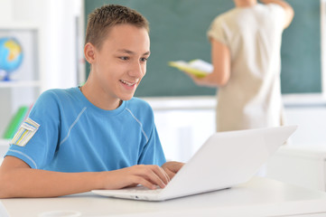 Obraz premium Portrait of cute little boy using laptop at classroom