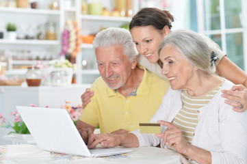 Happy senior couple with adult daughter using laptop