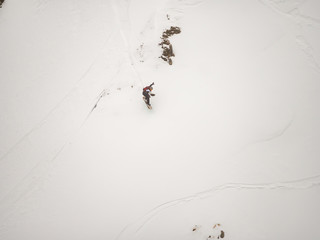 freerider snowboarder down the steep slope of white snow and trees in the mountains of the Caucasus