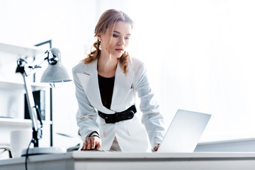 concentrated businesswoman in formal wear using laptop at workplace