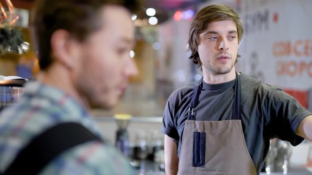 Close-up of a barist and a client talking in a cafe, client service, friendly talk.