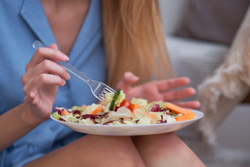 young woman is eating salad at home, diet concept. disgruntled person, depression from having to diet, lack of fat in the diet.