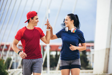 Happy couple running across the bridge. Healthy lifestyle.