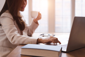 Beautiful asian business woman drinking coffee in white modern office background.