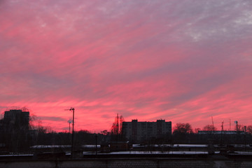 Red sunset above multistory house. Big pink cloud above evening city