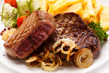 Grilled beefsteak with french fries and vegetable salad on white background
