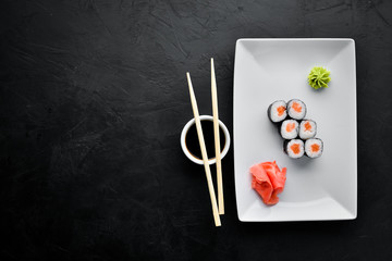 Sushi roll maki with salmon. Japanese cuisine. Top view. On a black stone background.