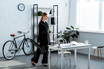 beautiful businesswoman in black clothes standing at office and looking at notebook