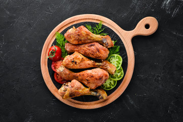 Baked Chicken legs on a black stone background. Meat. Top view. Free copy space.