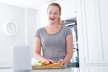 Woman Preparing Food At Home Asking Digital Assistant Question