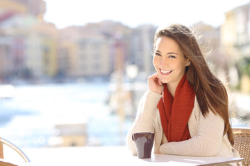 Happy woman looking at camera in a coffee shop of a port