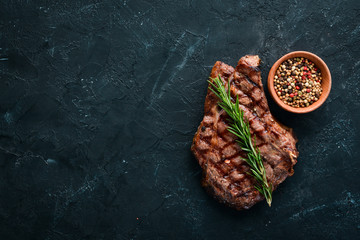 Veal steak on a bone on a black background. Free space for your text. Top view.