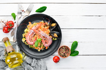 Bulgur with shrimp, mussels and vegetables. On the old background. Top view. Free space for your text.