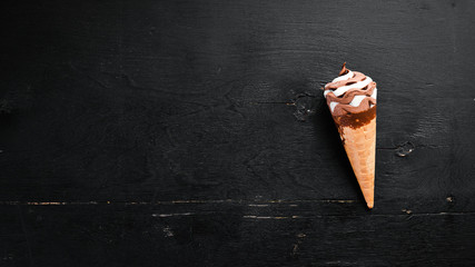 Ice cream in a waffle cup on a black background. Top view. Free copy space.