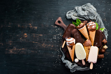 A set of ice cream with chocolate, nuts and jam. On a black background. Top view. Free copy space.