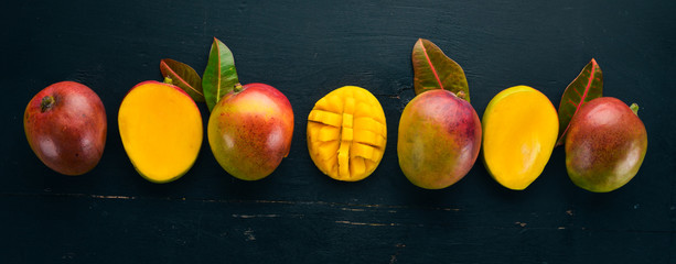Mango with leaves on a black wooden background. Tropical Fruits. Top view. free space for your text.