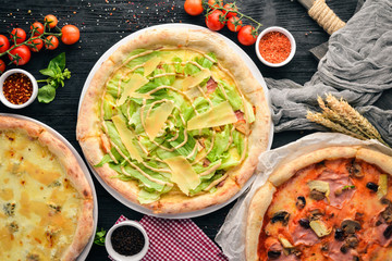 A set of Italian pizza. Italian cuisine. On a black wooden background. Free copy space. Top view.