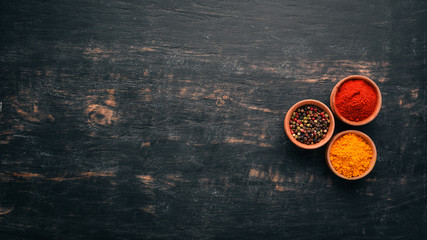 A set of spices and herbs. Indian cuisine. Pepper, salt, paprika, basil, turmeric. On a black...