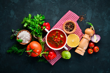 Tomato soup with onion, cucumber and paprika. Top view. On a black background. Free space for text.